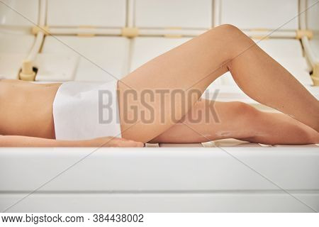Legs Of Young Lady Lying On The Machine For Beauty Treatment