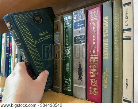 Moscow, Russia, August 2020: Close-up Of A Bookshelf With Books By Russian Writers. Hand Pulls Out D