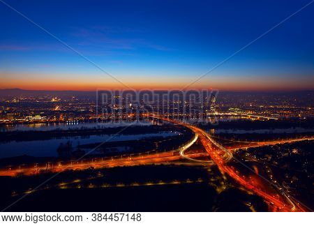 Aerial View Of Night Vienna . Illuminated Cityscape And Danube River In Wien
