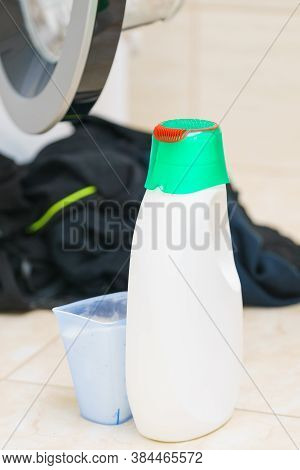 Washing Powder Liquid Detergent And Measuring Cup Next To Machine In Bathroom. Household Duties, Clo