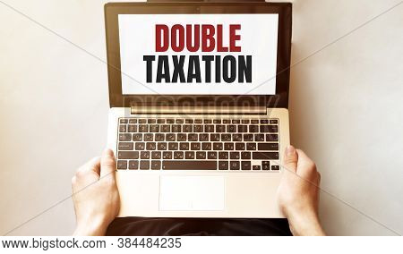 Young Man Checking His Laptop, Top View. Text Double Taxation