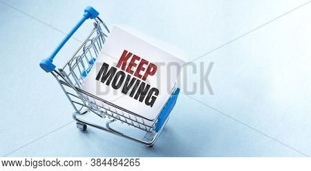 Shopping Cart And Tex Keep Moving On White Paper Note List. Shopping List Concept On Blue Background