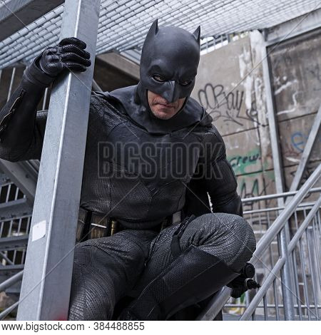 Umea, Norrland Sweden - September 5, 2020: Batman Is Sitting On A Stair Railing And Looks Grim