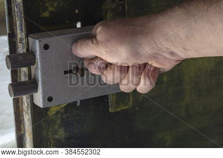 Close-up Of A Mans Hand Locking A Massive Door Lock On A Metal Door. The Inner Part Of The Door With