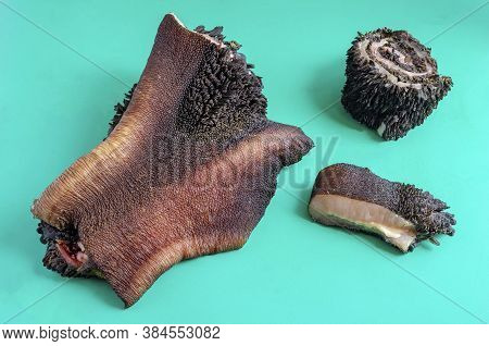 Pieces Of Raw Cow Stomach On Turquoise. Random Pieces Black Unpeeled Tripe With Grass Residues. Beef