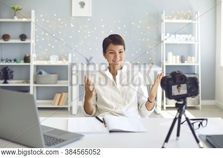 Cheerful Female Vlogger Recording A Video On Camera Sitting At Her Desk In Home Office