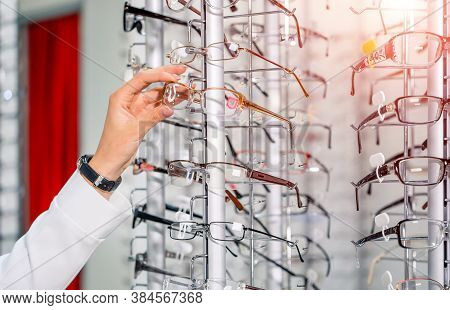 Showcase With Spectacles In Modern Ophthalmic Store. Hands With Glasses. Row Of Glasses At An Optici