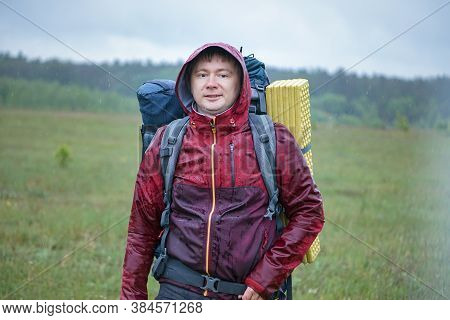 Hiker With A Large Backpack Getting Wet In The Rain While Traveling In The Mountains