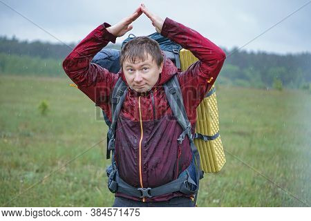 Hiker With A Large Backpack Getting Wet In The Rain While Traveling In The Mountains