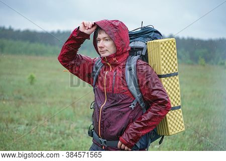 Hiker With A Large Backpack Getting Wet In The Rain While Traveling In The Mountains