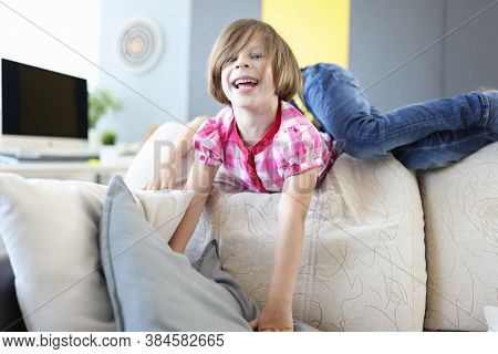 Girl And Boy Play Around On Couch At Home And Laugh. Baby Play And Pampering Concept