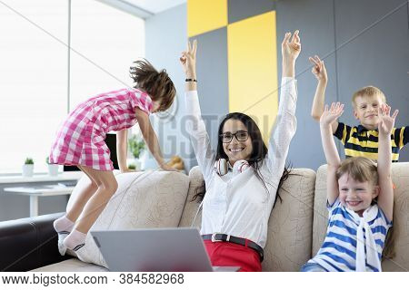 Woman, Boy And Two Girls Are Sitting On Couch And Laughing Happily And Raising Their Hands Up. Priva