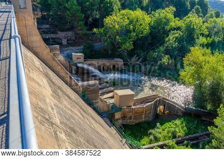 View Of The Regajo Reservoir Dam With A Stream Of Water Surrounded By Pine Forests. Architecture Con