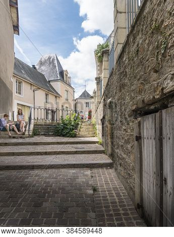 Sable Sur Sarthe, France, July 2019 - A Young Couple Sitting On Steps In The Town Of Sable Sur Sarth