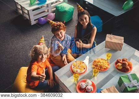 Three Kids Sitting At The Table And Celebrating Bday
