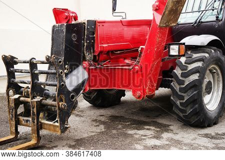 A Red Forklift Truck Stands On A Rough Terrain In The Yard.