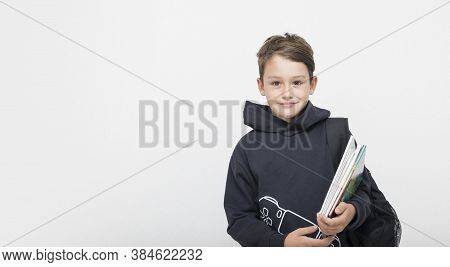 Cute Boy With A Backpack And Book And Notebok In Hands On A White Background. Learning, Education, S