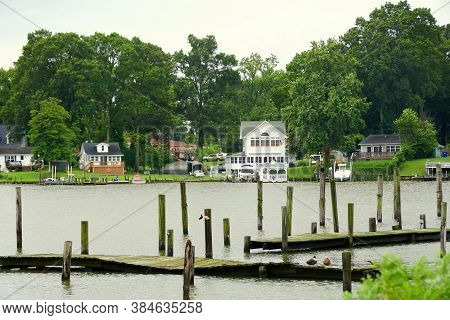 Cobb Island, Maryland, U.s.a - August 15, 2020 - The View Of The Wooden Dock And A Waterfront Home B