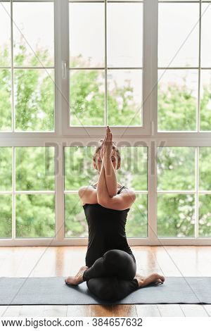 Yogi Mid Aged Woman Practicing Yoga, Doing Yoga Exercise Sitting In Variation Of Gomukasana Exercise