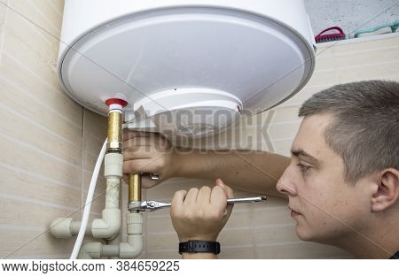 The Boiler Repair Technician Uses An Adjustable Wrench To Unscrew Or Tighten The Nut On The Pipe. In