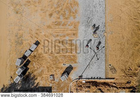 Worker With Vibratory Plate Compactor Compacting Sand At Road Or Sidewalk Construction Site Top View