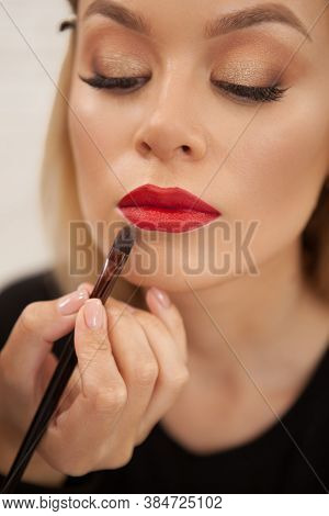 Vertical Closeup Of A Beautiful Woman Having Her Lips Painted With Red Lipstick