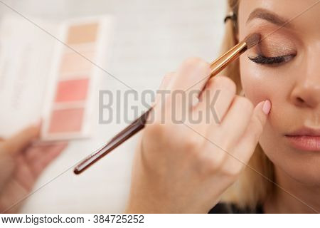 Cropped Shot Of A Makeup Artist Applying Eyeshadow From The Neutral Palette On Eyelids Of A Beautifu