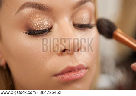 Charming Woman Getting Rofessional Makeup Done. Makeup Artist Applying Highlighter On Cheekbones Of 