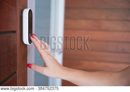 Close Up Of Woman Ringing Front Doorbell Equipped With Security Video Camera