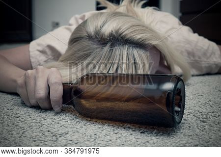 Woman Lying On The Floor With An Empty Alcohol Bottle Ans Sleeping, Overdosage And Female Alcoholism