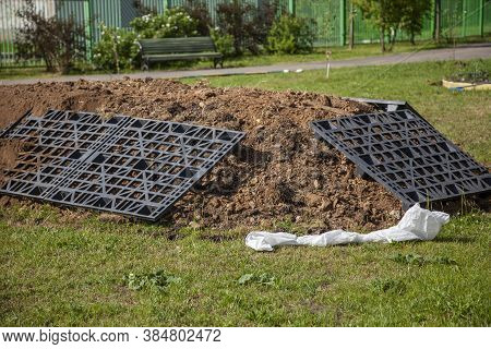 The Gardener Sprinkles A Flower Bed With A Shovel. Creation Of Landscape Design In The Garden. The M