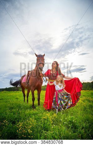 A Woman In A Bright Gypsy Dress And Image With A Horse In A Field With Green Grass. A Model Or Actre