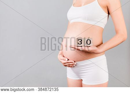 Cropped Portrait Of Pregnant In White Underwear Woman Holding Cubes Which Show Thirty Weeks Of Pregn