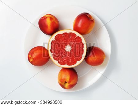 Fresh Red Grapefruits And Nectarines On A Plate. White Background. Top View