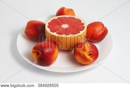 Fresh Red Grapefruits And Nectarines On A Plate. White Background. Side View