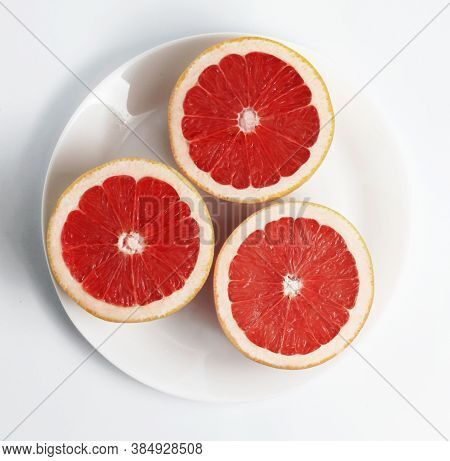 Fresh Red Grapefruits On A White Plate. White Background.