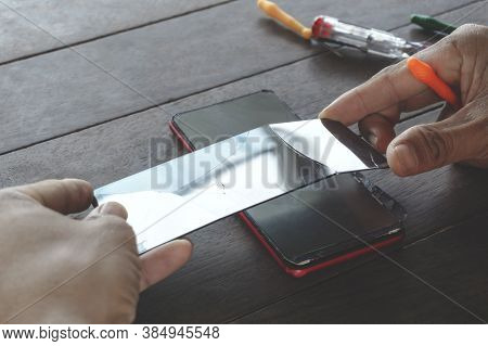 A Man Technician Holds A Black Smartphone Screen And Mini Tools Cracked Or Broken From A Drop For Re