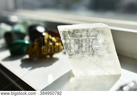 An Image Of Clear Icelandic Spar Calcite Charging On A White Window Ledge.