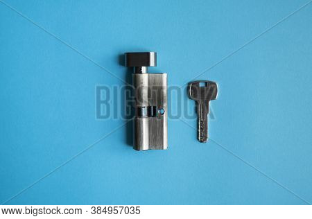 A Door Lock Cylinder Core With Key On The Blue Background. The Cylinder Of The Lock With Key. Instal