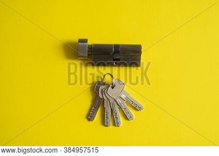 A Door Lock Cylinder Core With Keys On The Yellow Background. The Cylinder Of The Lock With Keys. In