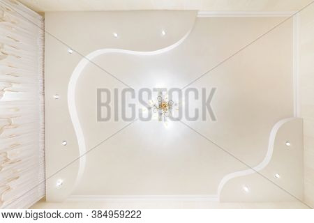 Stretch Ceiling White And Complex Shape With Halogen Spots Lamps And Drywall Construction In Empty R