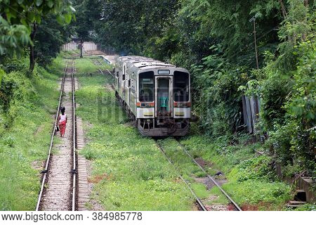 Behind Of Myanmarese Lady Villager Walking On The Railroad Tracks And Put The Black Bag Or Belonging
