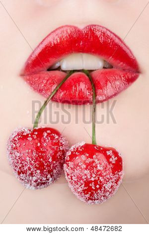 Mladá žena ústa s červených třešní pokryté cukru