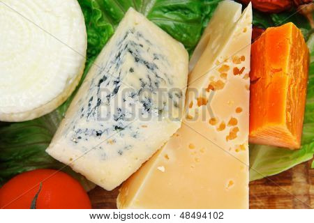 Roquefort med cheddar, parmesan og blød fetaost på træplade med tomater brød og oliven 