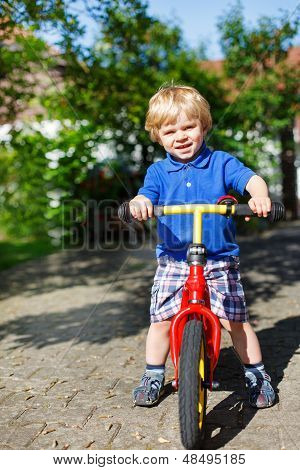 Ragazzino Toddler equitazione sulla sua bicicletta In estate
