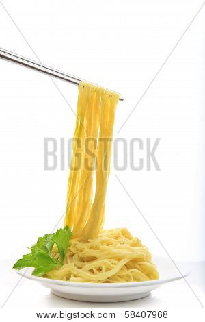 Steel Chopstick Holding Chinese Yellow Eggs Noodle On White Disk With Green Leaves Of  Celery Ready