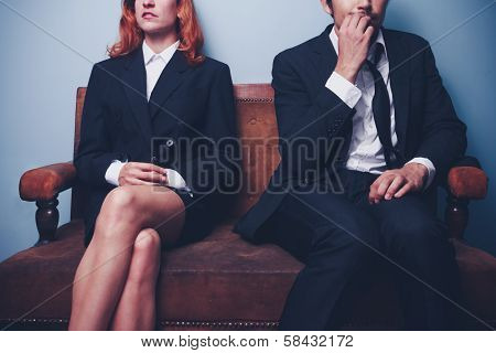 Nervous Businessman Sitting Next To Confident Businesswoman