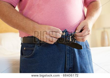 Close Up Of Overweight Man Trying To Fasten Trousers