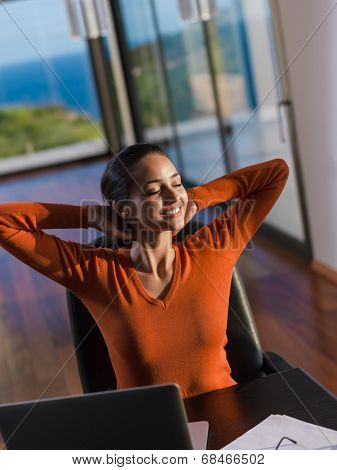 beautiful young woman relax and work on laptop computer while listening music on heaphones and read book at home