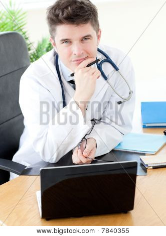 Usmívající se muž lékař s notebookem u stolu